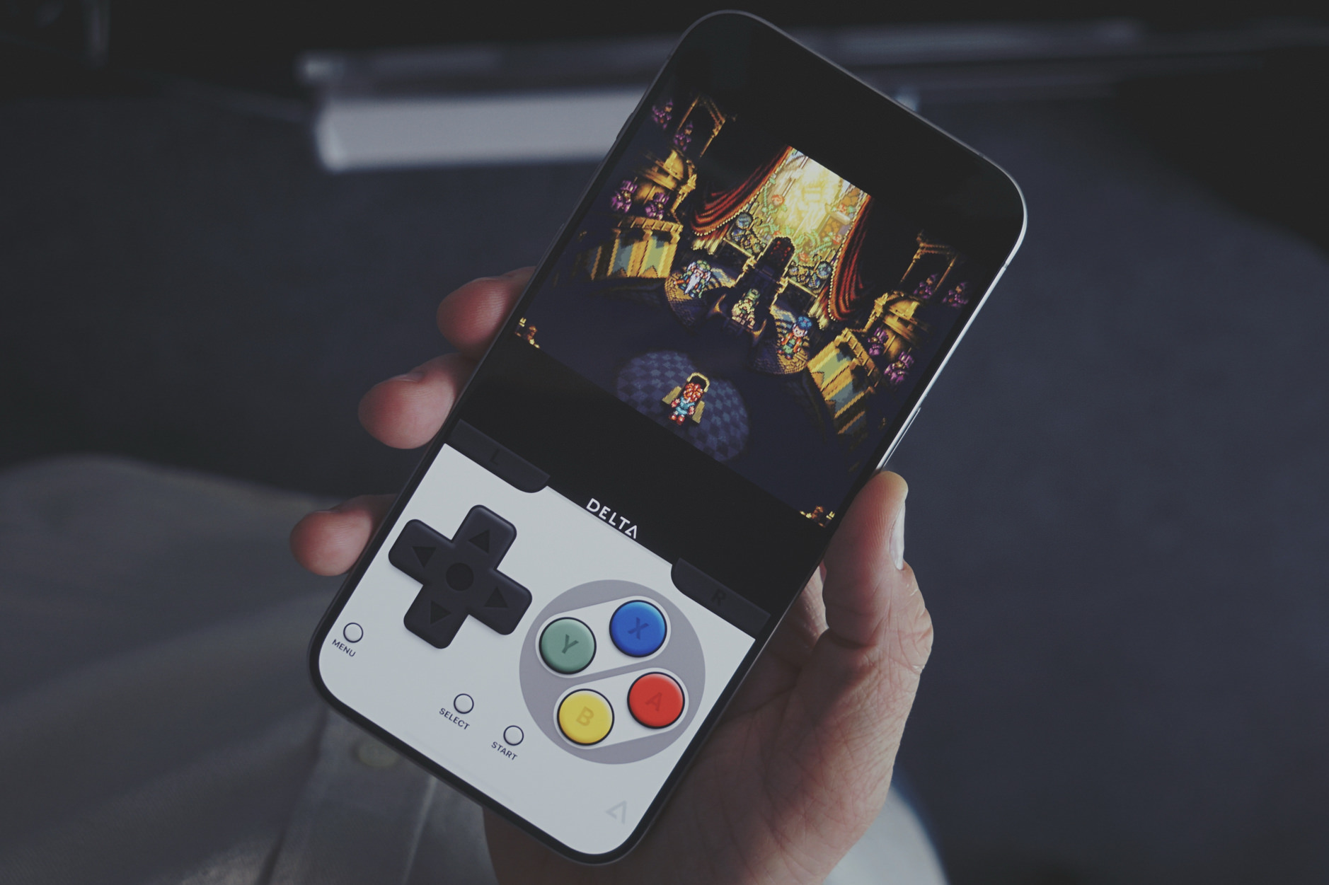 Auf dem Bild ist eine Hand zu sehen, die ein Smartphone hält, auf dessen Bildschirm Chrono Trigger, ein klassisches Videospiel, im Delta-Emulator dargestellt ist. Das Smartphone hat virtuelle Tasten im Stil eines alten SNES-Spielcontrollers.