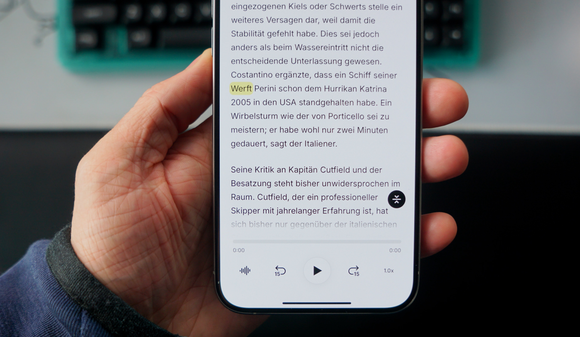 Das Bild zeigt eine Hand, die ein Smartphone hält, auf dessen Bildschirm ein deutscher Text zu sehen ist. Der Text scheint von einem Artikel oder einer Nachricht zu handeln, in dem es um ein Schiff der Werft Perini geht, das dem Hurrikan Katrina 2005 in den USA standgehalten hat.