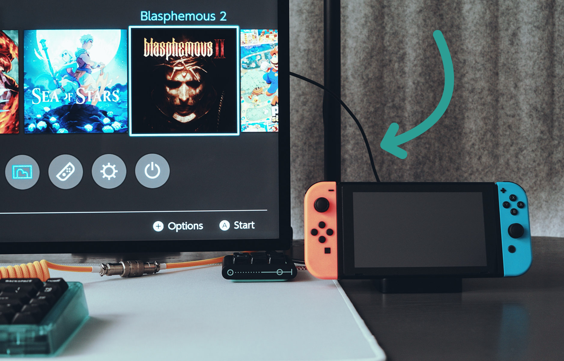 Das Bild zeigt eine Spielkonsole, eine Nintendo Switch, die an Apples Studio Display angeschlossen ist. Auf dem Bildschirm sind Spielecover zu sehen, darunter "Sea of Stars" und "Blasphemous II". 