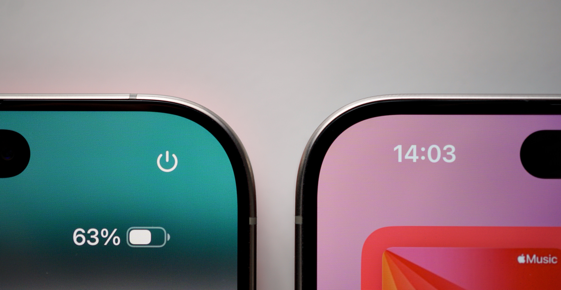 Das Bild zeigt die oberen Ecken von zwei iPhones. Auf dem linken Display ist der Akkustand mit 63 % und ein Ausschalt-Symbol zu sehen. Das rechte Display zeigt die Uhrzeit 14:03 und einen Teil des Apple Music-Logos.