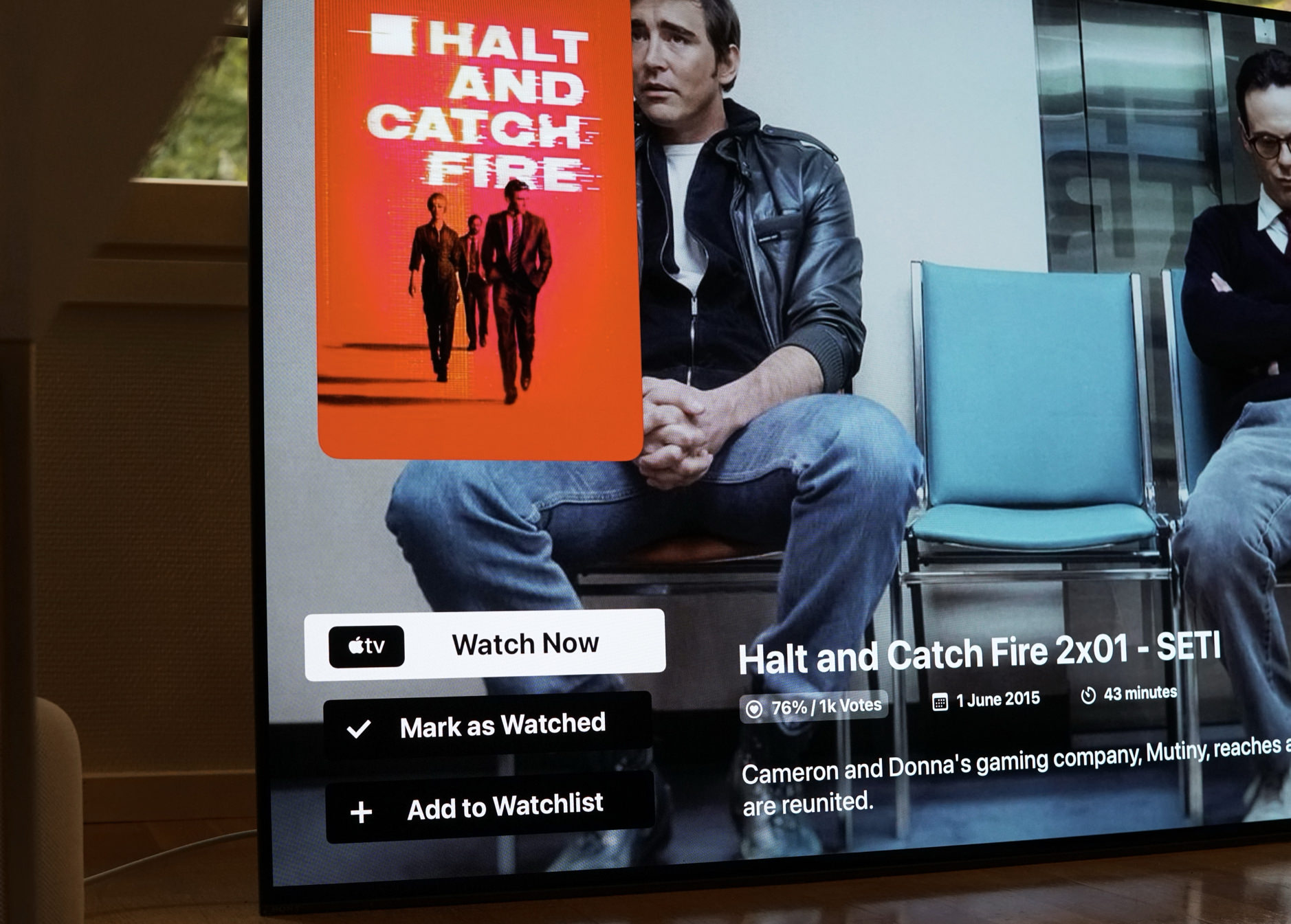 Das Bild zeigt eine Streaming-Oberfläche auf einem Fernseher mit der Serie "Halt and Catch Fire". Die Episode 2x01 mit dem Titel "SETI" wird angezeigt, zusammen mit einer Bewertung von 76% basierend auf 1.000 Stimmen. Es gibt Optionen zum Ansehen, als gesehen markieren und zur Merkliste hinzufügen.