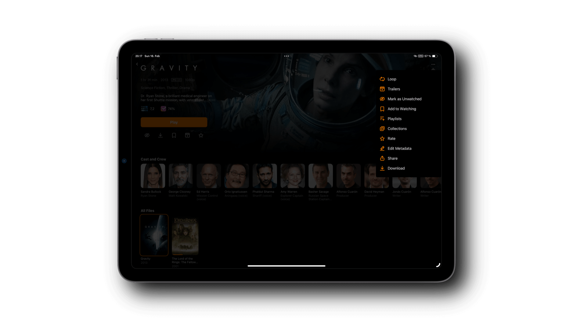 Das Bild zeigt ein Tablet mit einer Benutzeroberfläche, auf der der Film Gravity angezeigt wird. Es gibt Informationen zum Film, wie Genre, Bewertungen und Besetzung, sowie eine Liste von Optionen wie "Abspielen", "Bewerten" und "Herunterladen". Unten sind weitere Filme und die Besetzung des Films sichtbar.